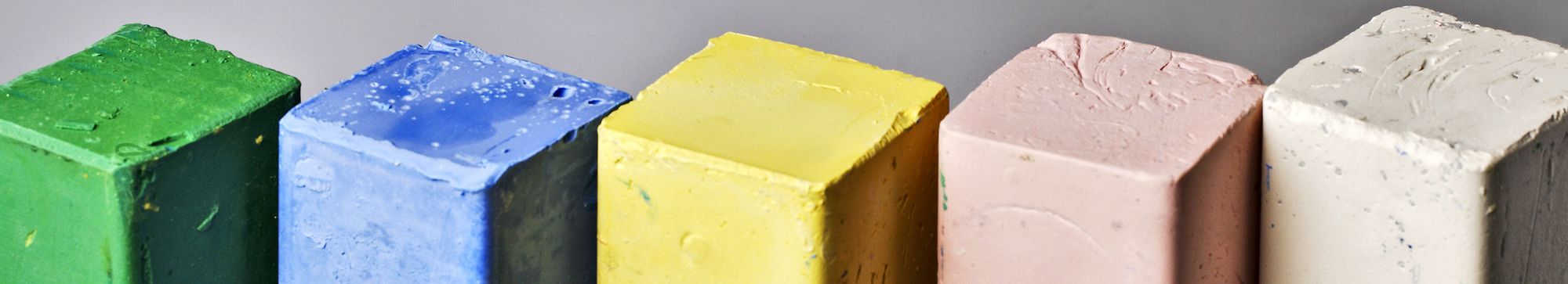 Panetti di pasta abrasiva di colori diversi allineati su un piano neutro
